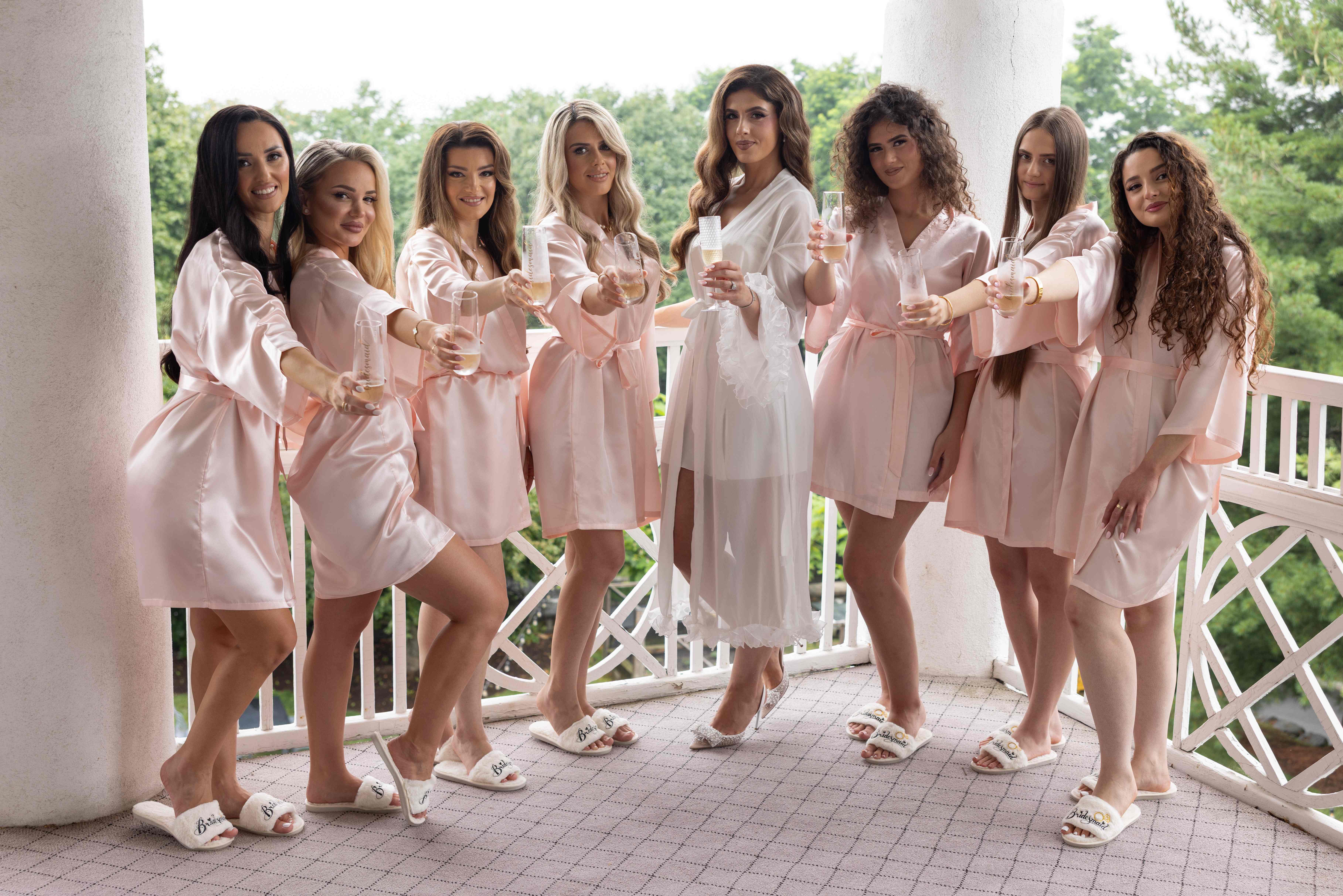 Bridesmaids in pink robes celebrating with champagne before ceremony