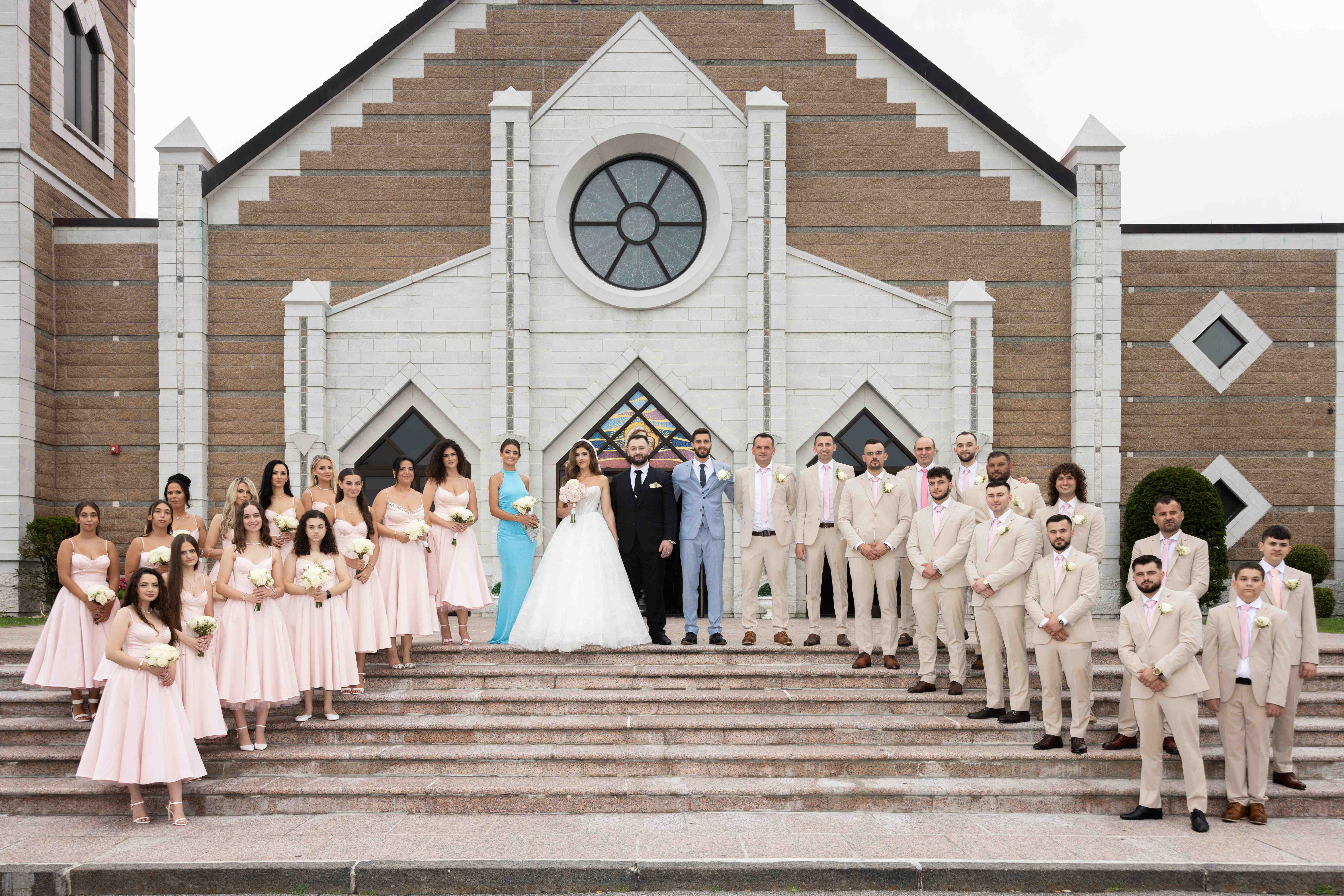 Complete wedding party on church steps with bride, groom, bridesmaids and groomsmen