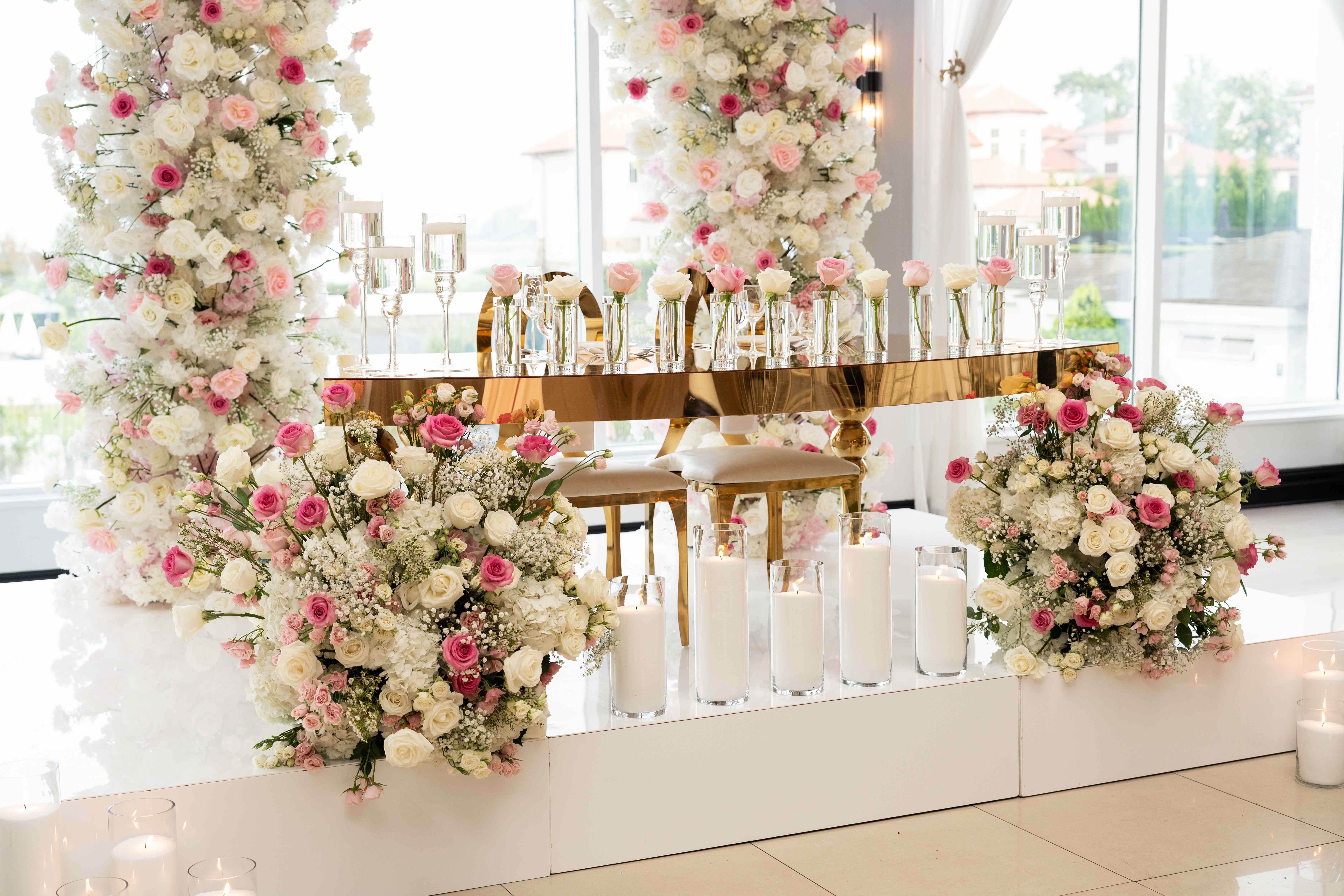 Luxurious gold mirrored sweetheart table with individual rose stems in crystal vases